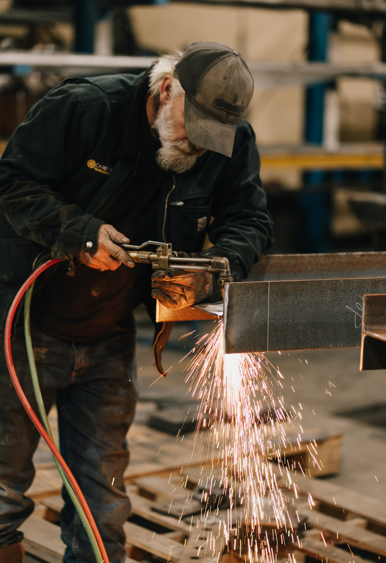 Veteran Carey Brothers fabricator cutting a steel beam with a torch