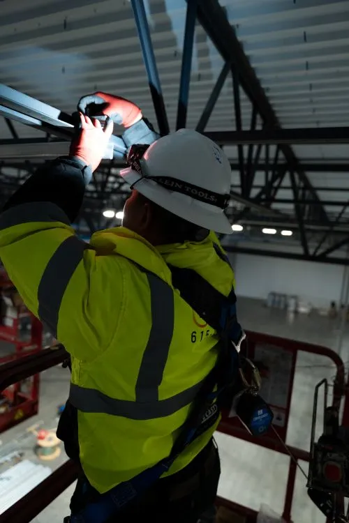 Phaze Electric electrician installing overhead conduit from a lift