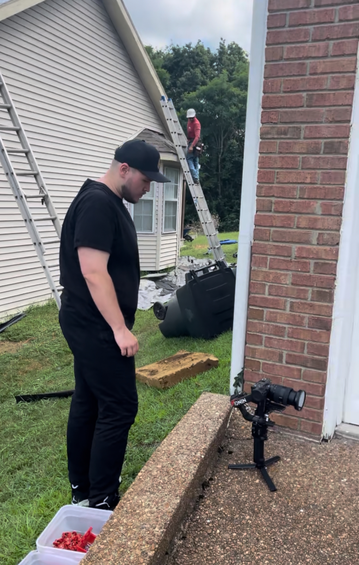 HLM videographer with gimbal filming a roofing crew on a residential job site