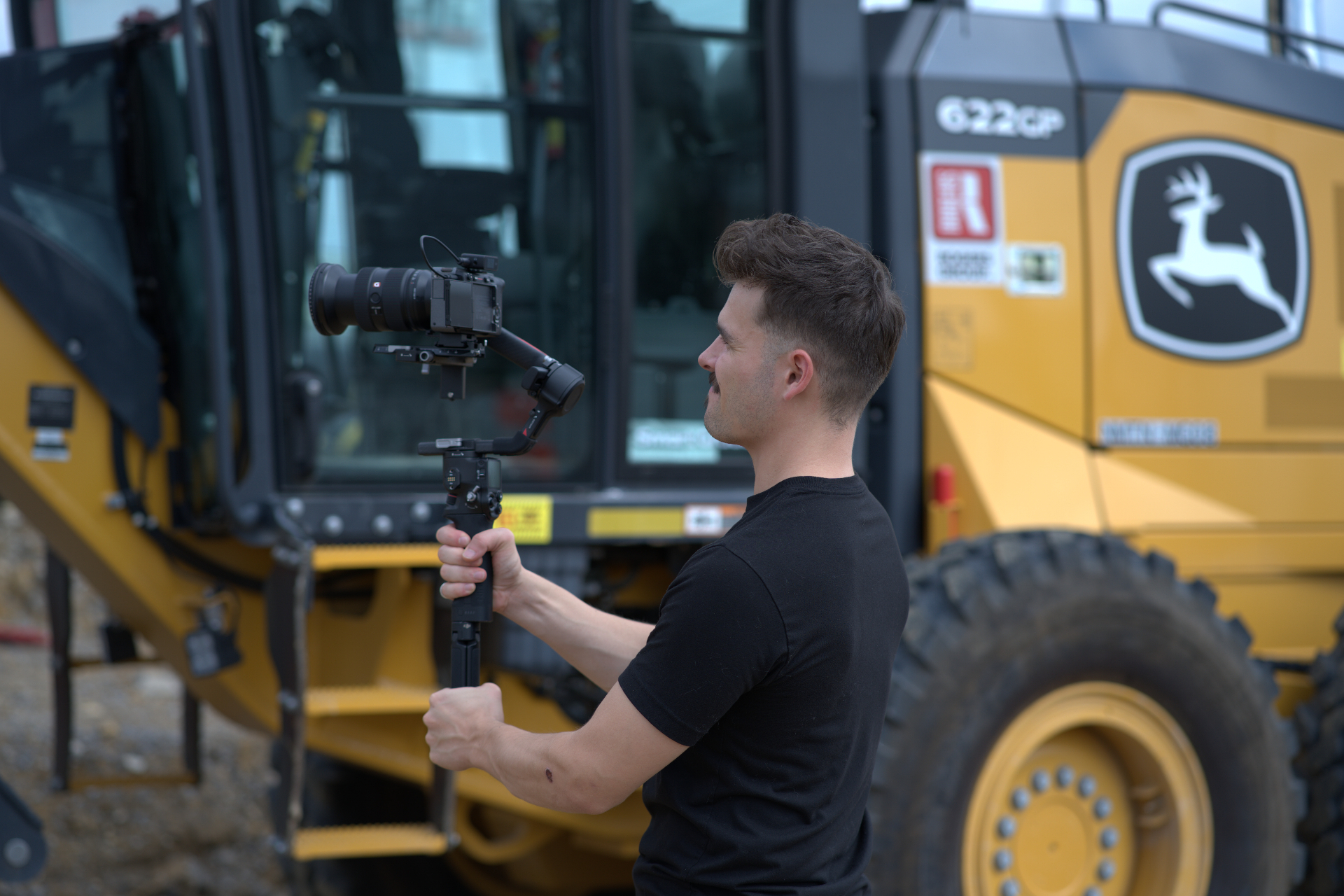 HLM operator filming a John Deere motor grader on a job site