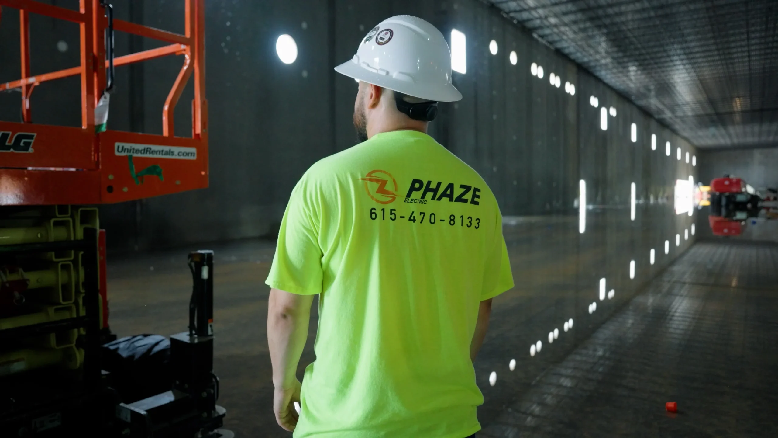 Phaze Electric electrician in a hard hat walking a commercial warehouse job