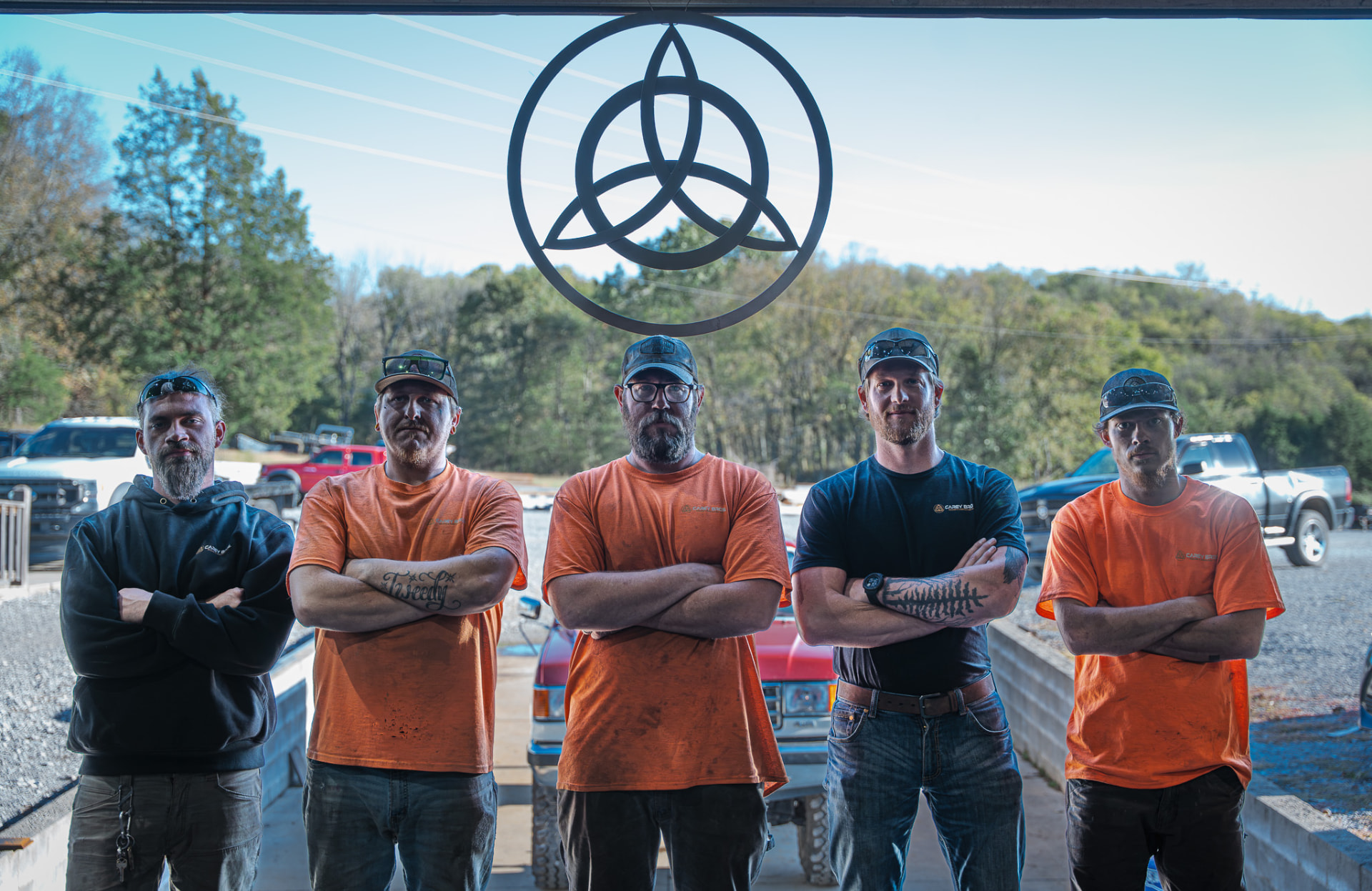 Carey Brothers Welding and Fabrication crew standing with arms crossed under the shop's Celtic knot sign