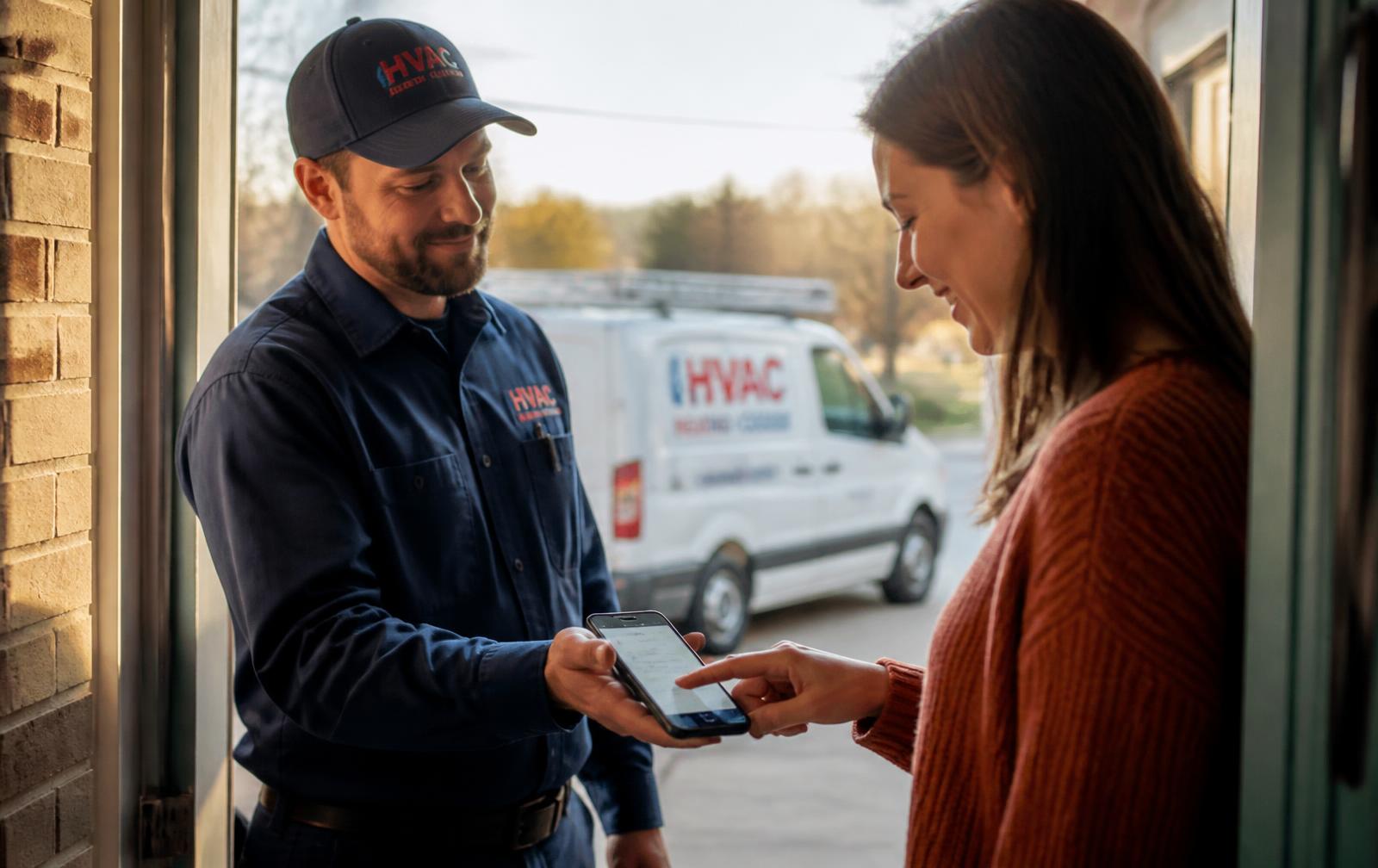 Service technician handing his phone to a homeowner to leave a review at the front door